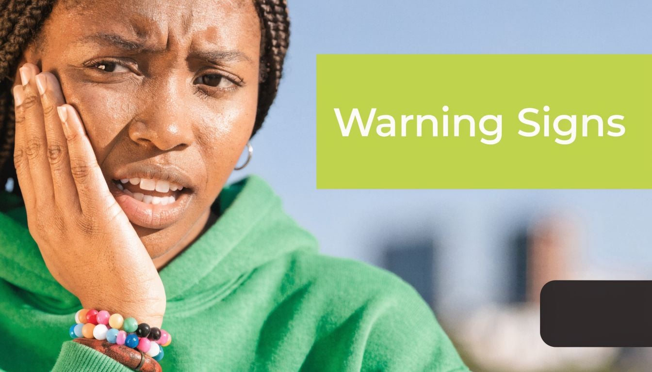 A young woman with a concerned expression holding her jaw as if experiencing dental pain.