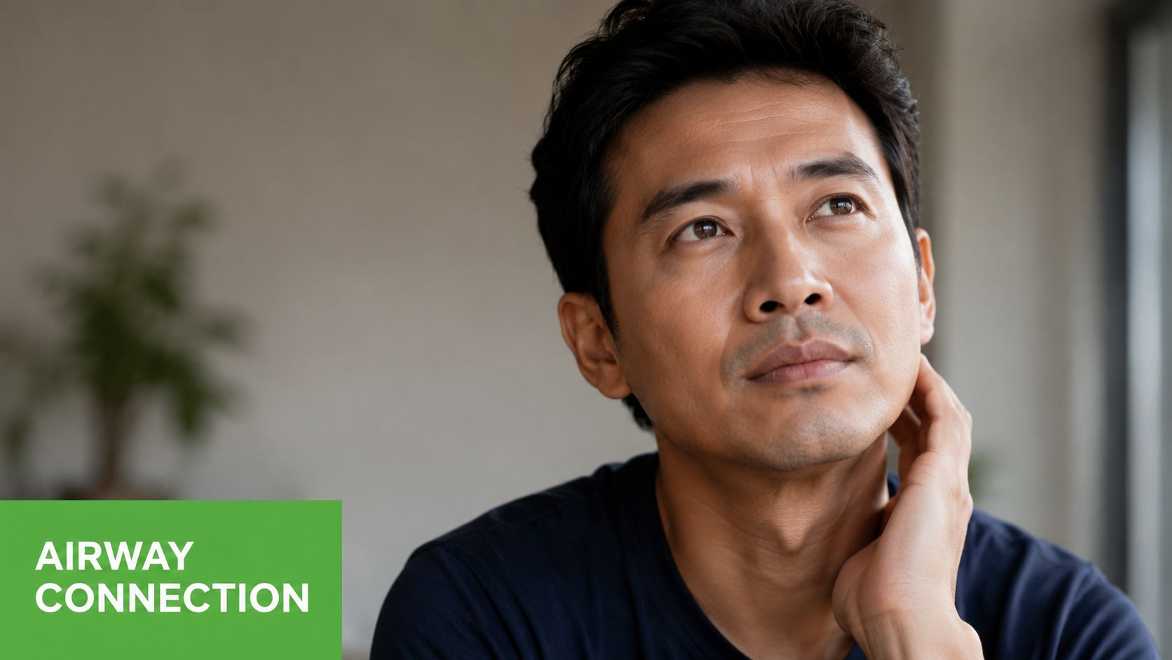 An Asian man looking thoughtful while resting his hand against his chin near his neck.