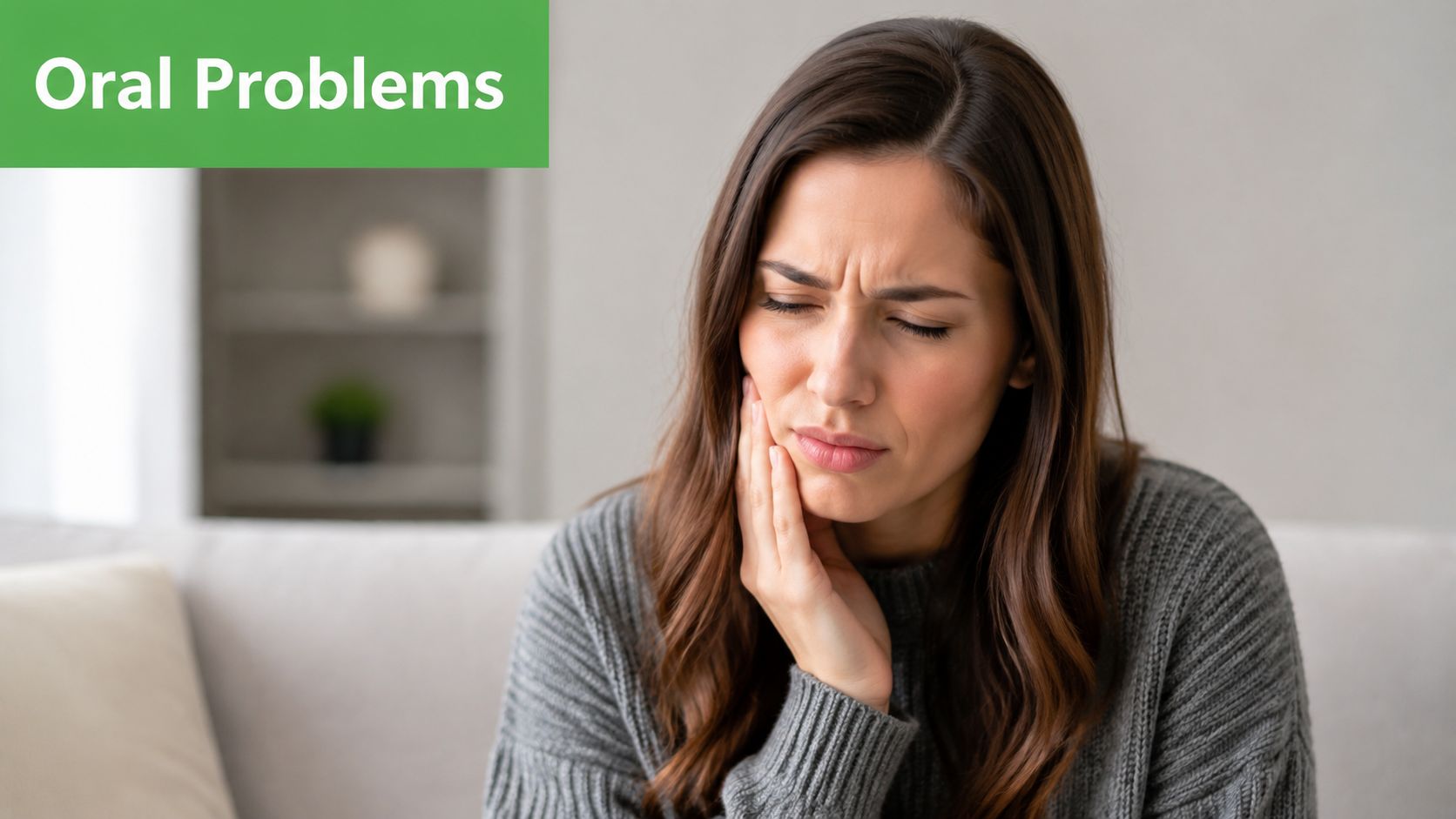 A young woman sitting on a couch touching her cheek, showing signs of oral pain and discomfort.