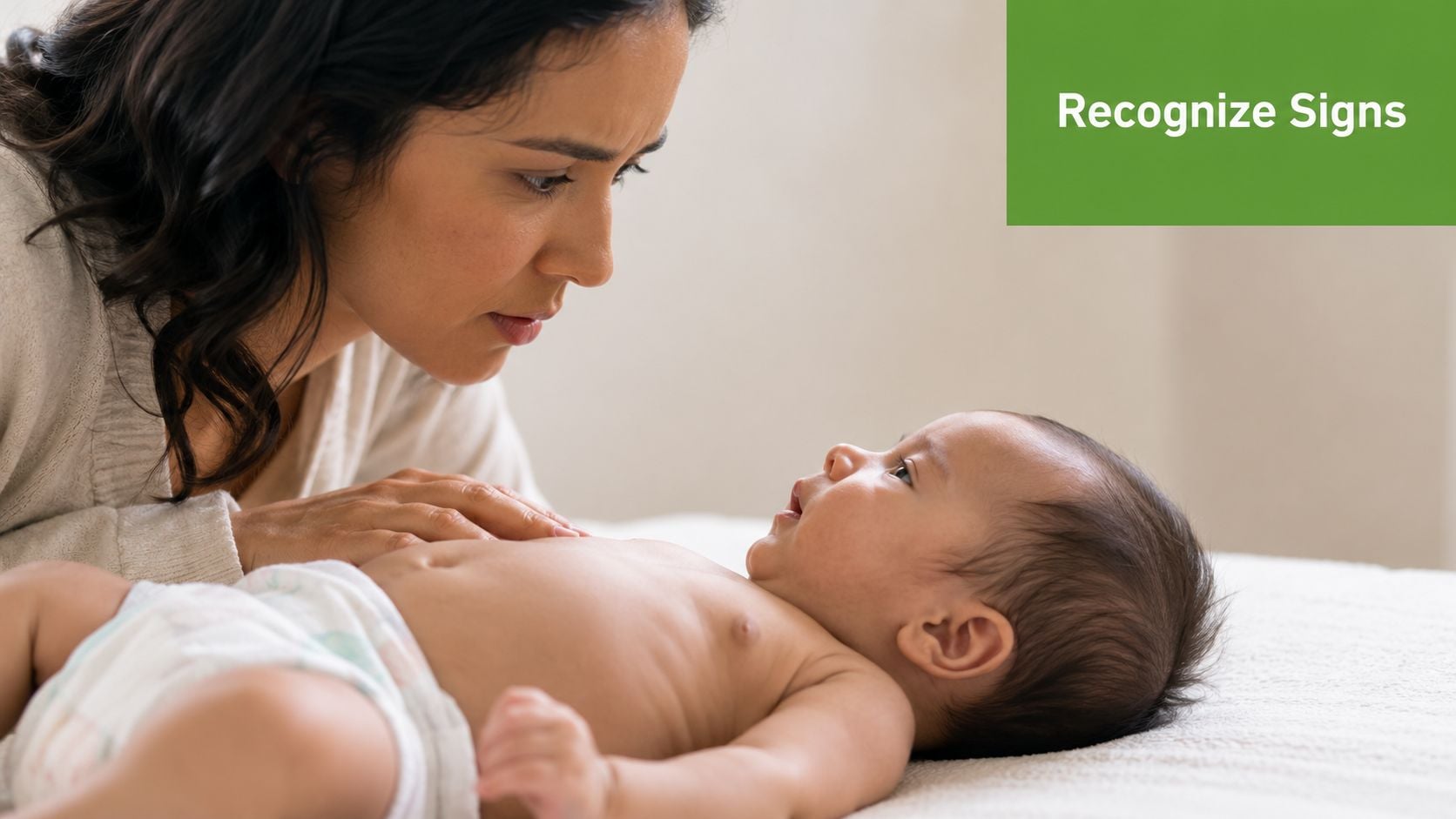 A concerned mother watching her newborn baby while resting her hand on the infant's chest.