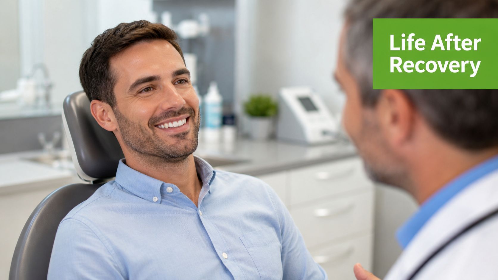 A smiling male patient sitting in a dental chair speaking with his doctor during a consultation.